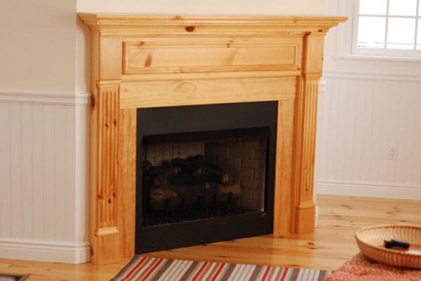 A fireplace with wood mantle and surround in living room.