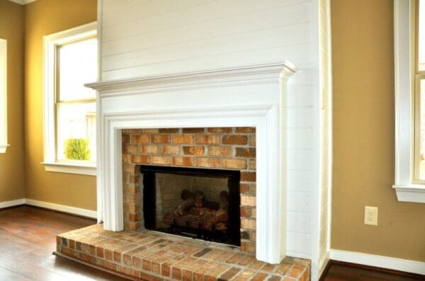 A fireplace with brick surround and white walls.