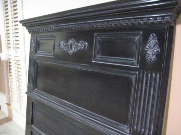 A black wooden dresser with ornate carvings on the front.