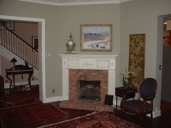 A living room with a fireplace and a painting on the wall.