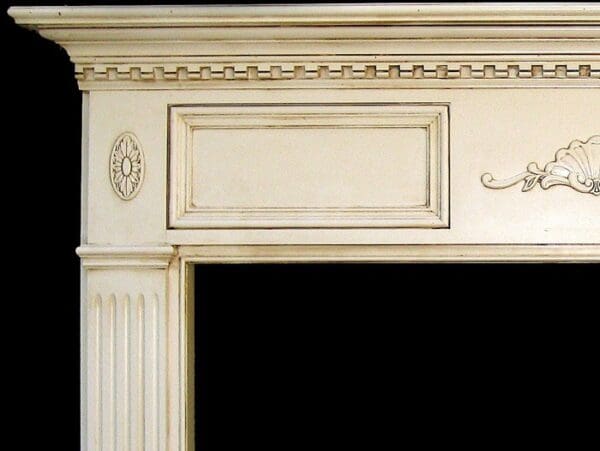 A white fireplace with an ornate design on the mantle.