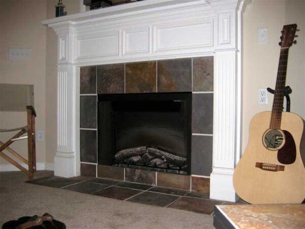 A fireplace with tile surround and white mantel.