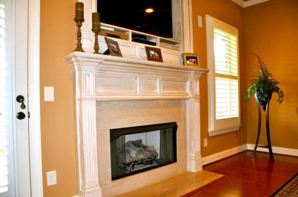 A fireplace with a television above it and a window.