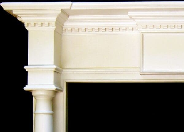 A white fireplace with pillars and an archway.