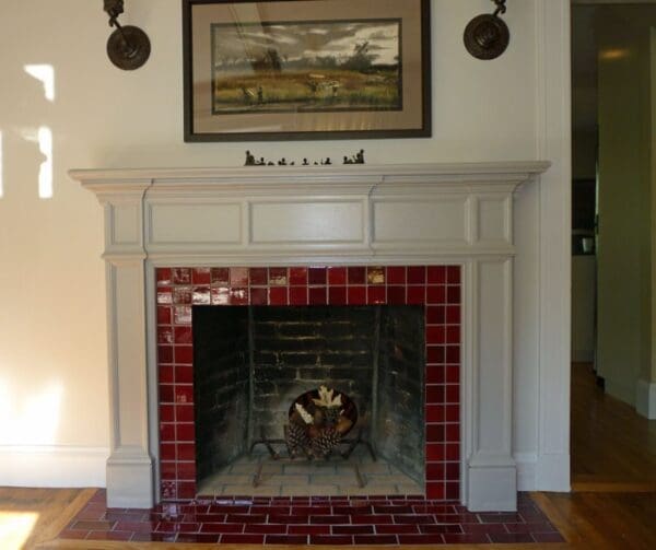 A fireplace with red tile surround and white mantel.