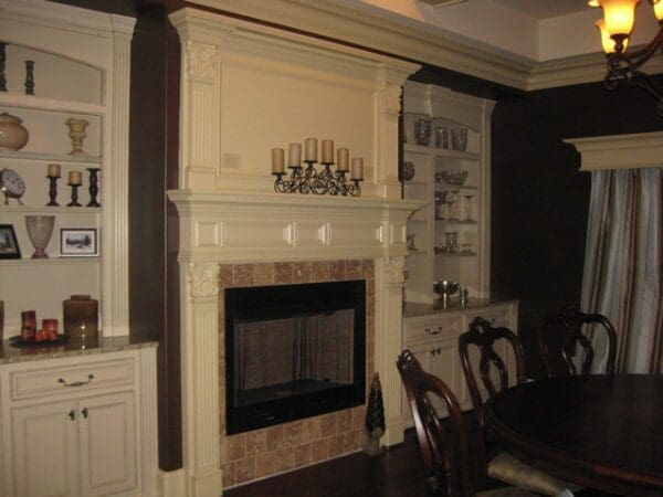 A fireplace in the corner of a room with a table and chairs.