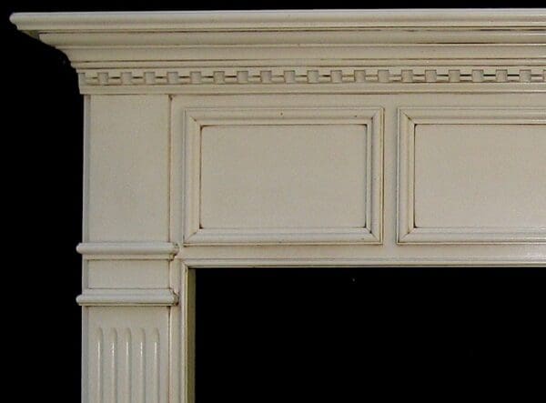 A fireplace mantle with a white finish and decorative moldings.