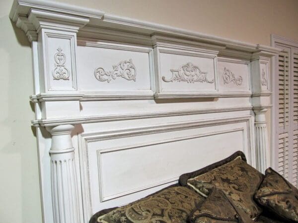 A white headboard with decorative carvings on the top of it.