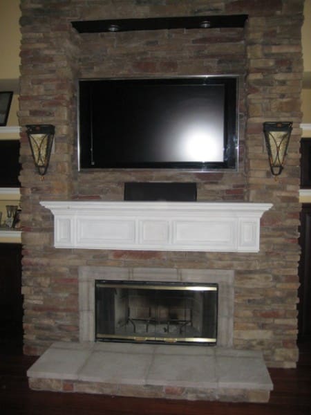 A fireplace with a flat screen tv mounted above it.