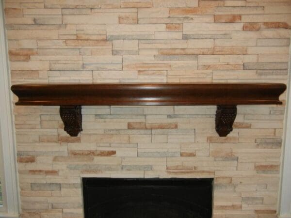 A fireplace mantle with wood trim and stone wall.