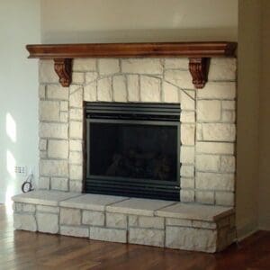 A fireplace with wood mantle and stone surround.