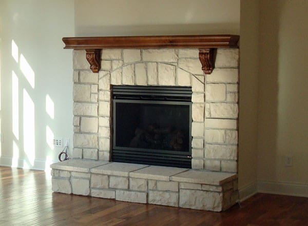 A fireplace with wood mantle and stone surround.