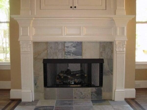 A fireplace with marble tile and white trim.