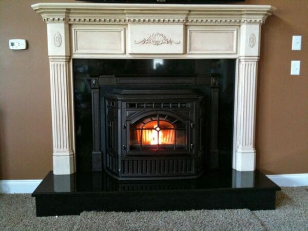 A fireplace with a black marble surround and white trim.