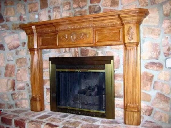 A fireplace with wood mantle and brick surround.