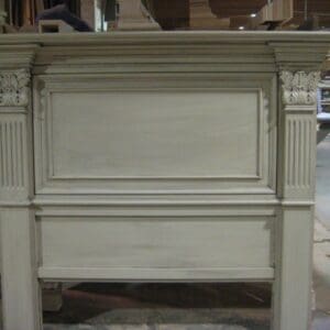 A white fireplace mantle with an old headboard.