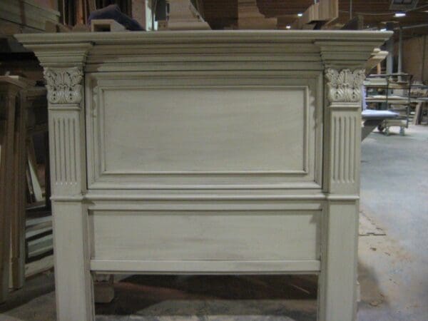 A white fireplace mantle with an old headboard.