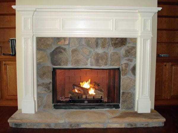 White fireplace with stone surround and fire