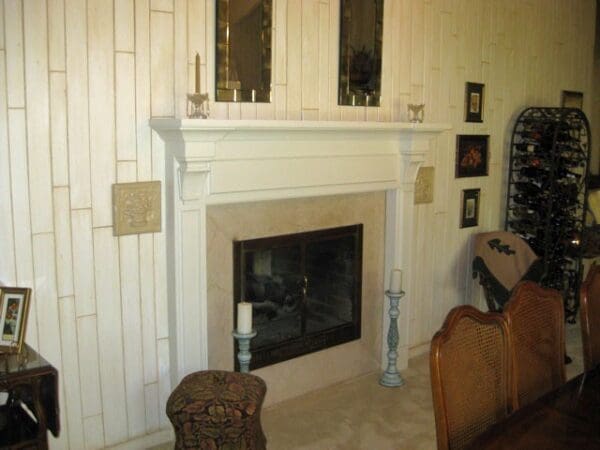 White fireplace with candles and wood paneling.