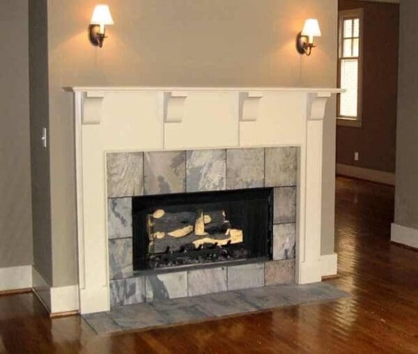 White fireplace with stone surround and wood floor.