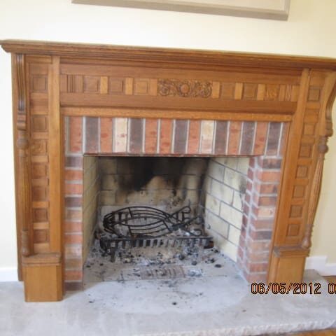 A fireplace with wood mantle and brick surround.