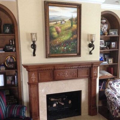 A fireplace in the living room with a painting above it.