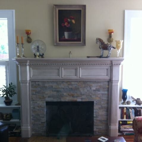 A fireplace with a painting above it in the corner.