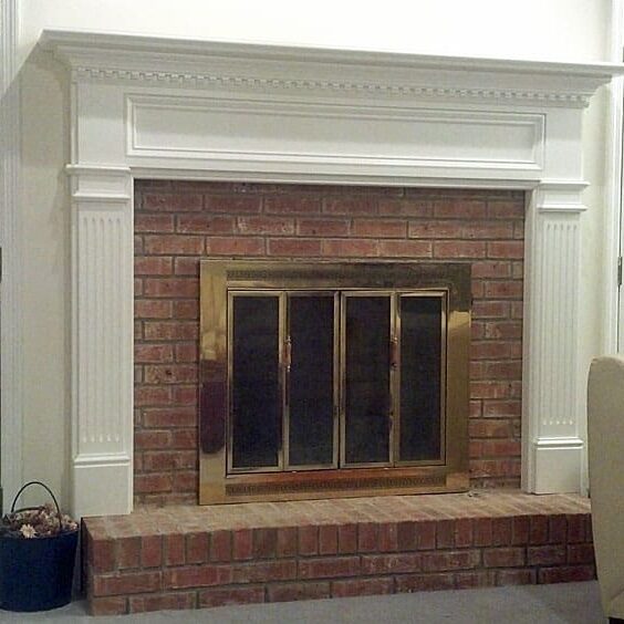 A fireplace with brick surround and white mantle.